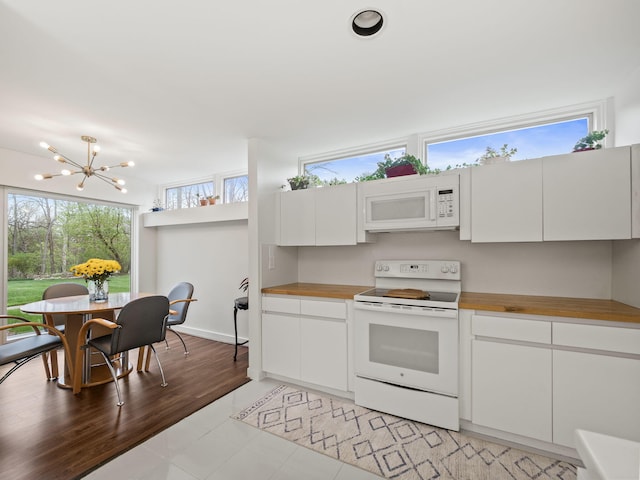 kitchen featuring an inviting chandelier, white appliances, white cabinetry, and butcher block counters