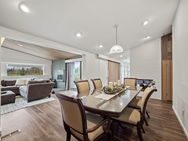 dining room featuring visible vents, a brick fireplace, wood finished floors, and lofted ceiling