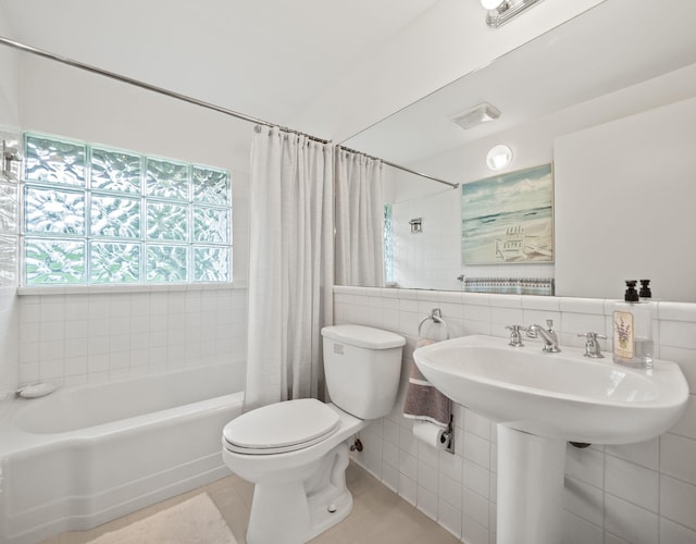 full bath featuring tile patterned floors, shower / bath combination with curtain, toilet, and tile walls