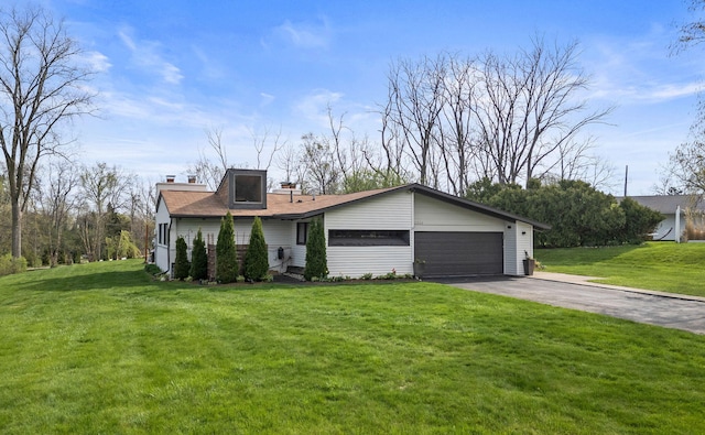 view of front of house featuring an attached garage, a chimney, a front lawn, and aphalt driveway
