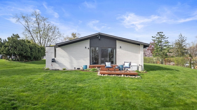 back of property with a lawn, a deck, and brick siding