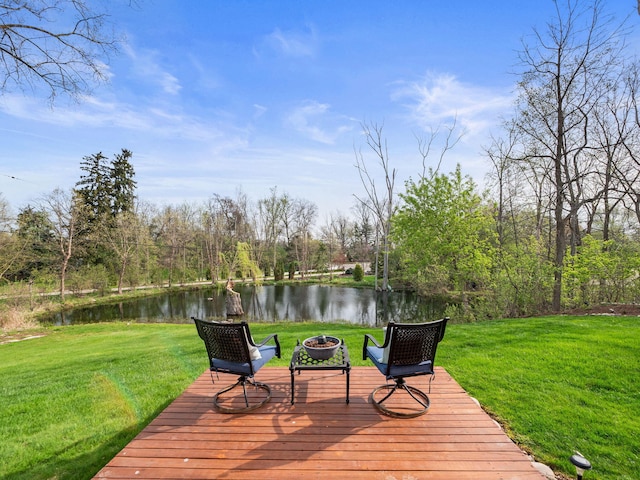wooden terrace with a lawn, a water view, and a fire pit