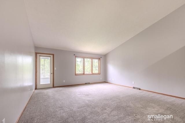 unfurnished room with carpet floors, vaulted ceiling, and a wealth of natural light