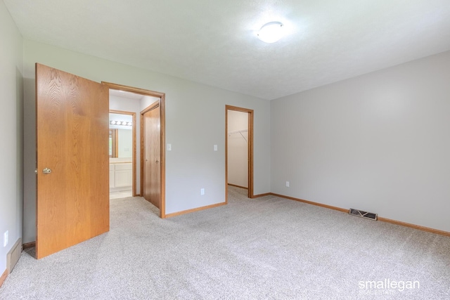 interior space with a walk in closet, visible vents, carpet floors, baseboards, and a closet