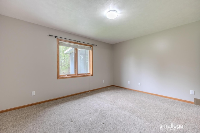 spare room featuring baseboards, visible vents, and light carpet
