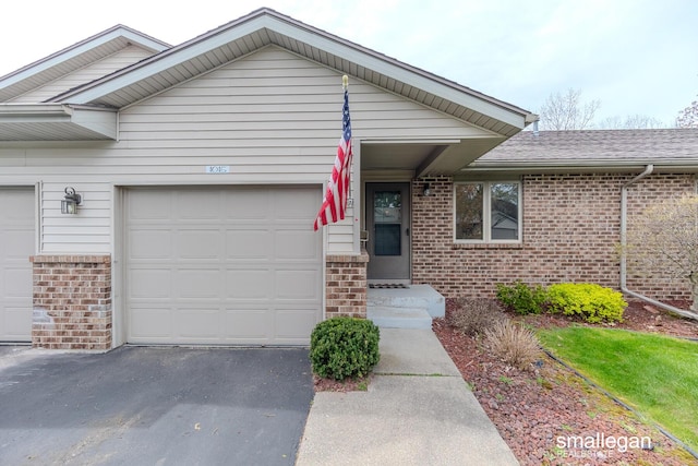ranch-style home featuring an attached garage, aphalt driveway, and brick siding