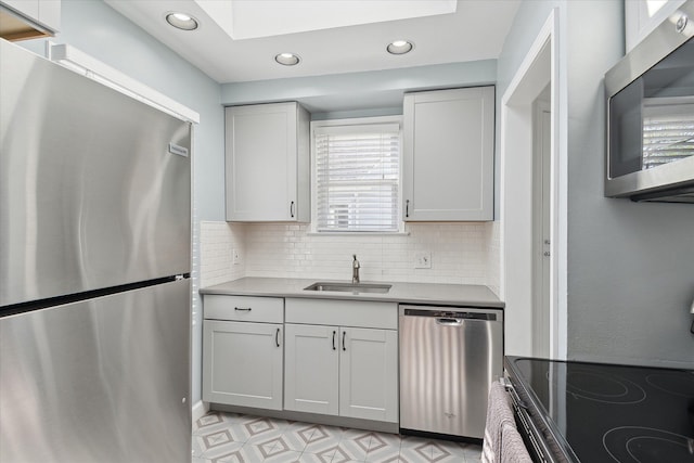 kitchen with a skylight, tasteful backsplash, a sink, stainless steel appliances, and recessed lighting
