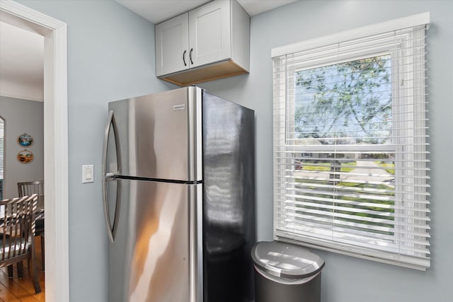 kitchen featuring freestanding refrigerator, white cabinetry, and wood finished floors