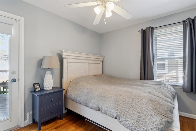 bedroom with baseboards, ceiling fan, multiple windows, and wood finished floors