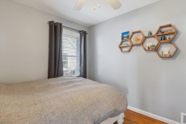 bedroom with baseboards, ceiling fan, wood finished floors, and visible vents