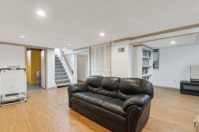 living area featuring light wood finished floors, recessed lighting, baseboards, visible vents, and stairway