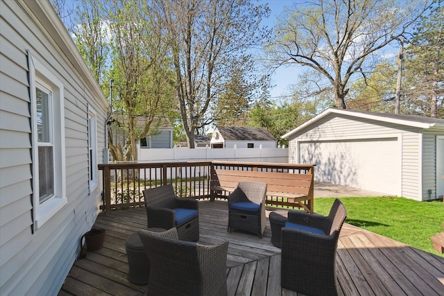 wooden terrace featuring a detached garage, fence, and an outdoor structure