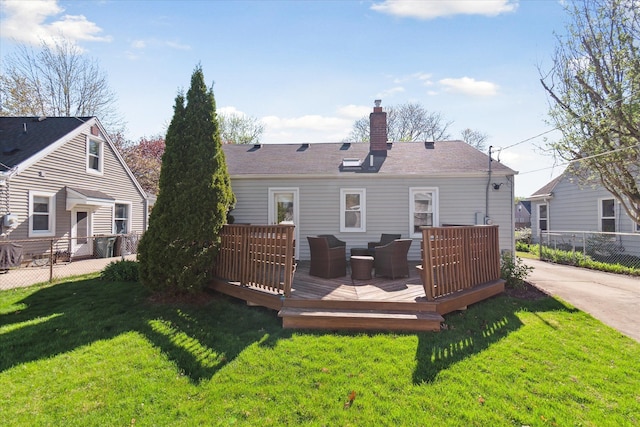 rear view of house with a chimney, fence, a yard, and a wooden deck