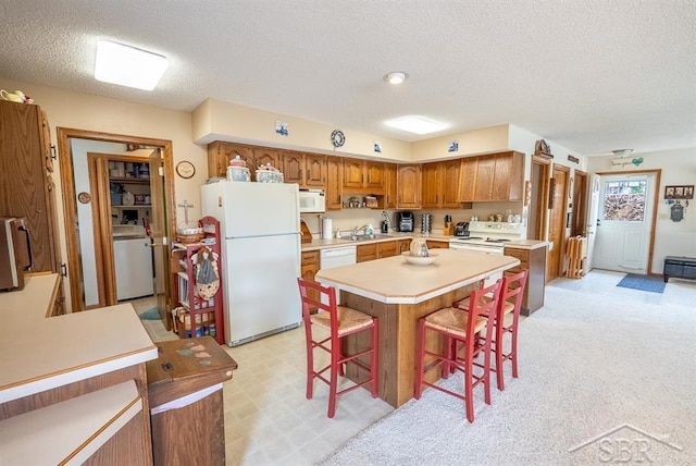 4438 N Verity Rd, Sanford, MI 48657 - kitchen with white appliances, light countertops, a textured ceiling, washer / dryer, and a kitchen bar