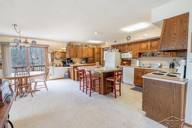 4438 N Verity Rd, Sanford, MI 48657 - kitchen featuring a sink, white appliances, a kitchen breakfast bar, brown cabinetry, and a kitchen island