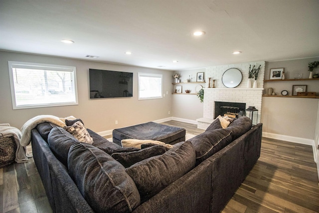 living area with recessed lighting, baseboards, a brick fireplace, and dark wood finished floors