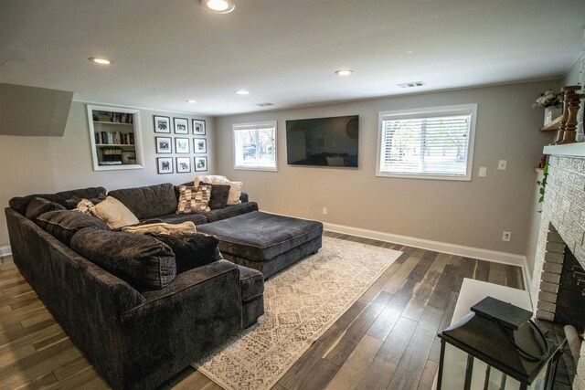 living room featuring a healthy amount of sunlight, a brick fireplace, dark wood-style floors, and visible vents