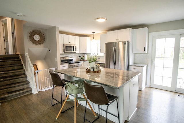 kitchen featuring light stone counters, decorative backsplash, dark wood-type flooring, and stainless steel appliances