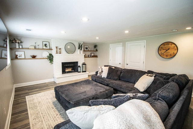 living room with visible vents, a brick fireplace, wood finished floors, baseboards, and recessed lighting