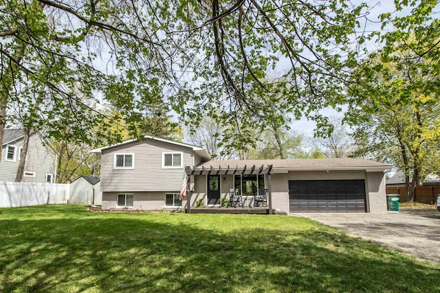 split level home featuring a garage, a front lawn, fence, brick siding, and driveway