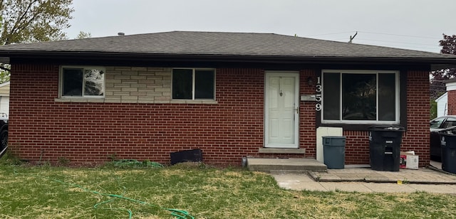 view of front facade featuring brick siding, roof with shingles, and a front lawn