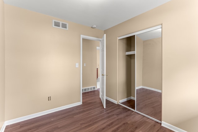 unfurnished bedroom with visible vents, baseboards, wood finished floors, and a closet