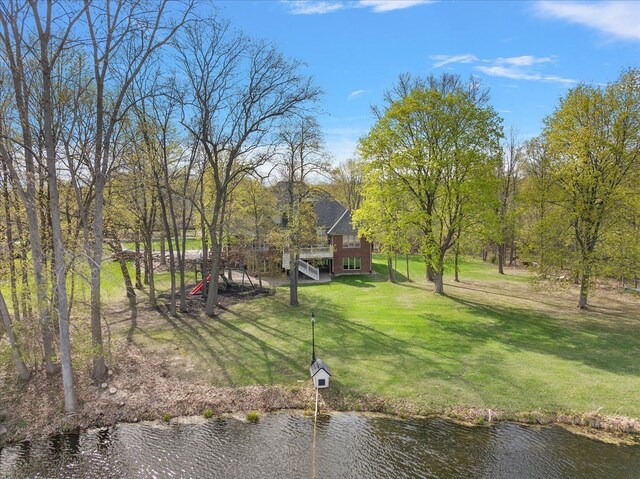 view of yard featuring stairway and a deck with water view