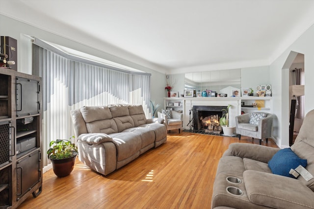 17172 Huntington Rd, Detroit, MI 48219 - living area with arched walkways, light wood-style flooring, and a high end fireplace