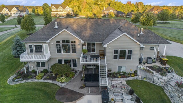 view of front of home featuring a residential view, stairs, a shingled roof, a front lawn, and a patio area