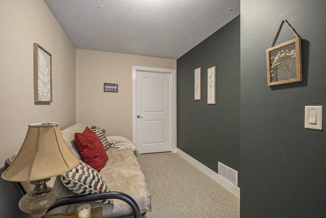 sitting room with carpet floors, a textured ceiling, visible vents, and baseboards