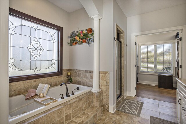 bathroom with ornate columns, tile patterned floors, a tub with jets, and a shower stall
