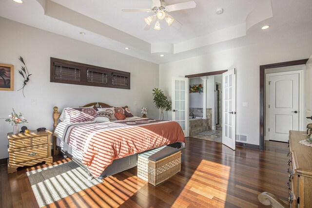 bedroom with french doors, a tray ceiling, wood finished floors, and visible vents