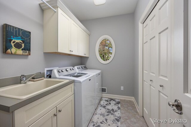 clothes washing area featuring cabinet space, a sink, separate washer and dryer, baseboards, and light tile patterned floors