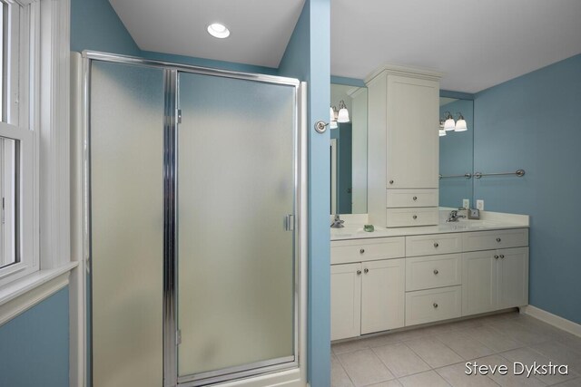 bathroom featuring a sink, double vanity, tile patterned floors, baseboards, and a stall shower