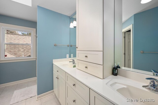 bathroom with baseboards, a sink, tile patterned floors, and double vanity