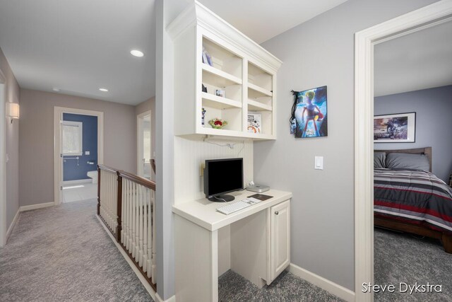 hallway featuring carpet flooring, baseboards, and an upstairs landing
