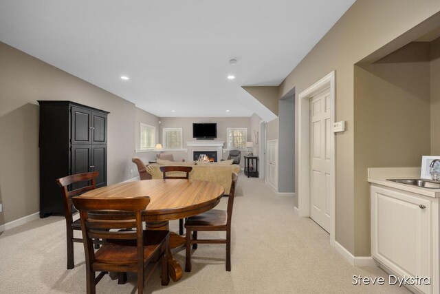 dining room with a glass covered fireplace, recessed lighting, and light colored carpet