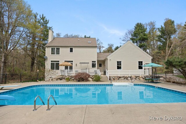 view of swimming pool with a diving board, a fenced in pool, fence, and a deck