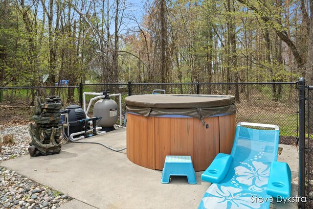 view of patio / terrace with a hot tub and fence