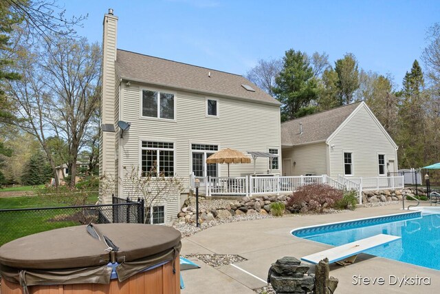 back of property featuring fence, a hot tub, a fenced in pool, a chimney, and a patio