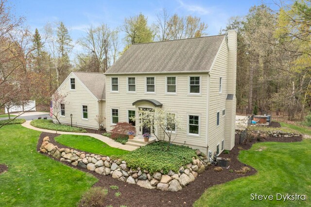 view of front of home featuring roof with shingles, central AC unit, a chimney, and a front yard