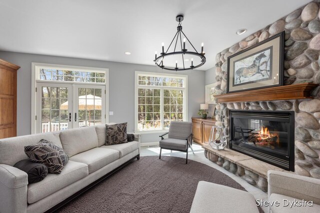 carpeted living area featuring french doors, a fireplace, baseboards, an inviting chandelier, and recessed lighting