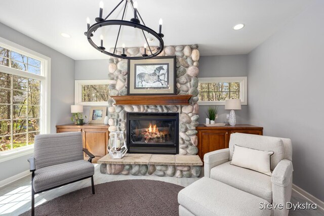 sitting room with baseboards, recessed lighting, a notable chandelier, and a fireplace