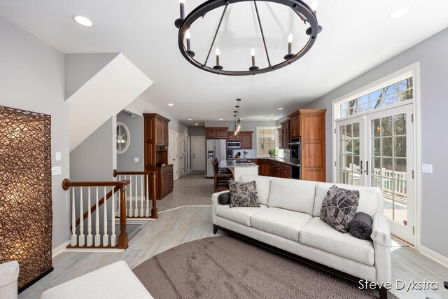 living area with baseboards, light wood-style floors, recessed lighting, french doors, and a notable chandelier