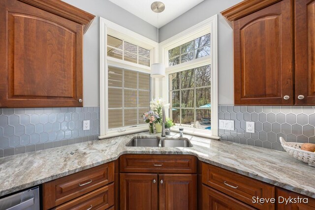 kitchen featuring light stone counters, a sink, dishwasher, and tasteful backsplash
