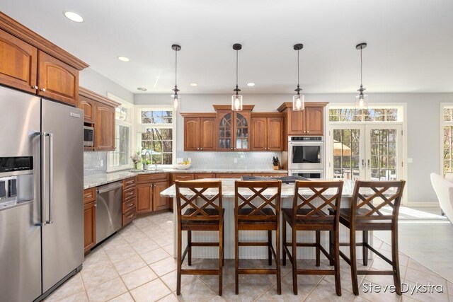 kitchen with plenty of natural light, decorative backsplash, stainless steel appliances, and brown cabinets