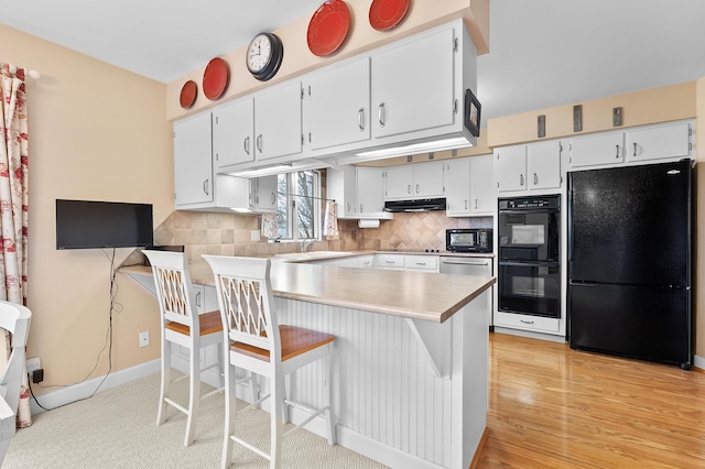 3529 E Lemon Creek Rd, Berrien Springs, MI 49103 - kitchen featuring black appliances, under cabinet range hood, a peninsula, and tasteful backsplash