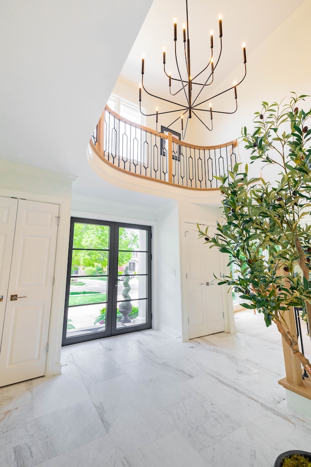 entrance foyer featuring healthy amount of natural light, a high ceiling, marble finish floors, a chandelier, and baseboards