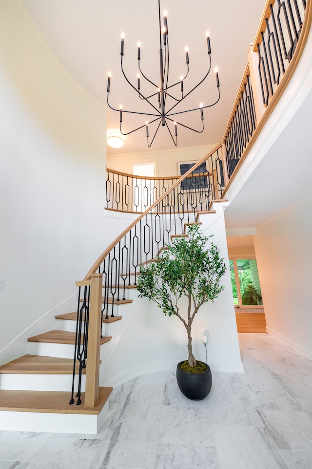 stairway with marble tiled floors, a towering ceiling, a chandelier, and baseboards