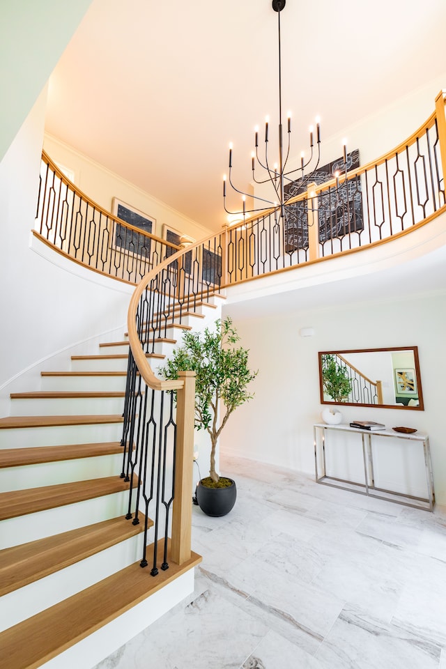 stairs with marble tiled flooring, a towering ceiling, and a chandelier